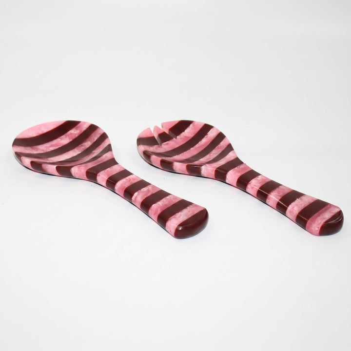 Two striped wooden serving utensils, likely a spoon and a turner, with alternating pink and dark reddish-brown wood grain patterns, shown on a plain white background.