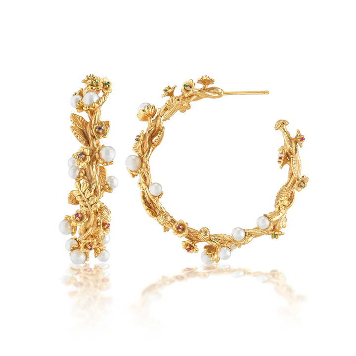 A pair of elaborate floral gold hoop earrings with pearl accents
