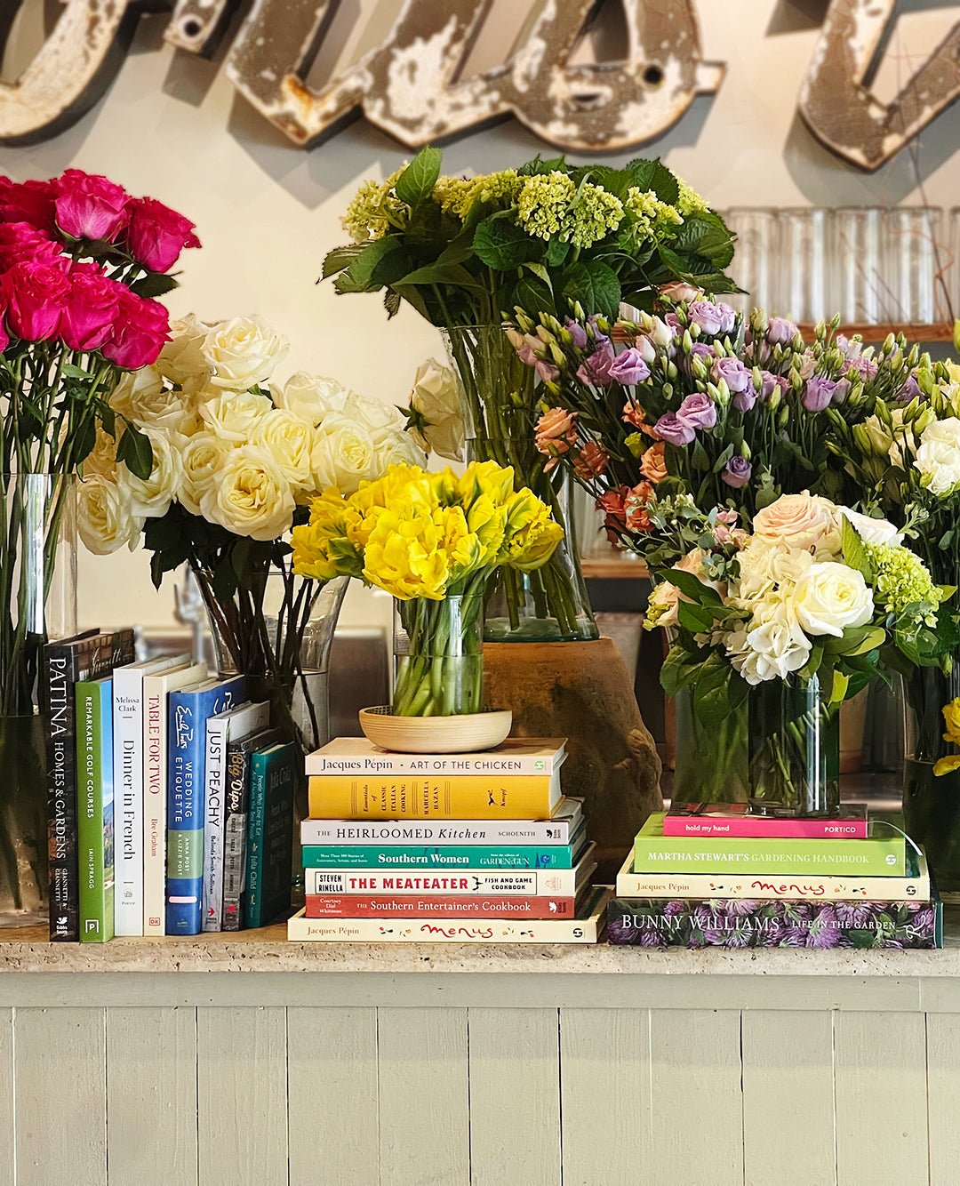 an assortment of books surrounded by flowers in vases
