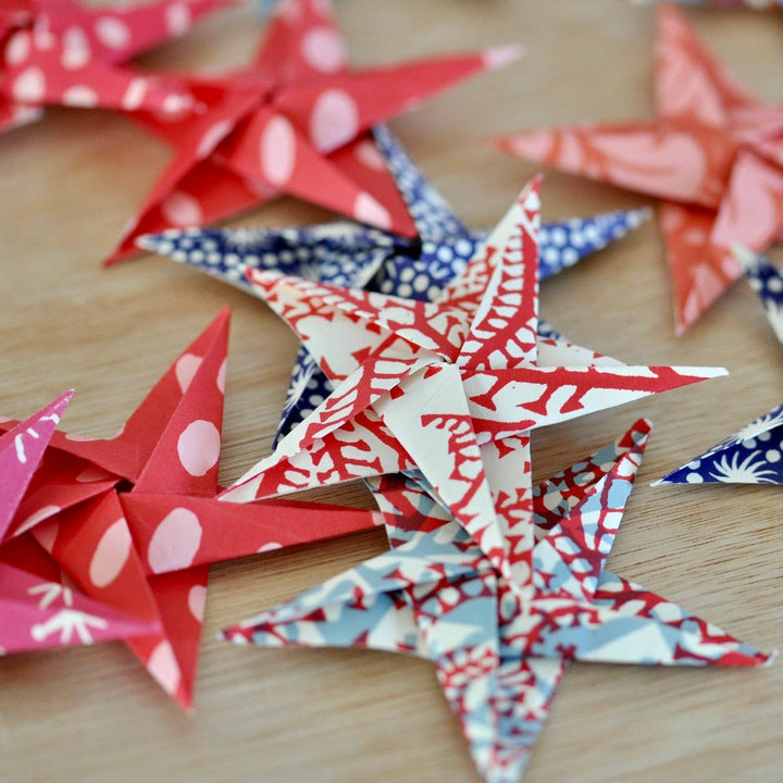 Colorful red, white, pink, and blue paper stars on a wooden surface