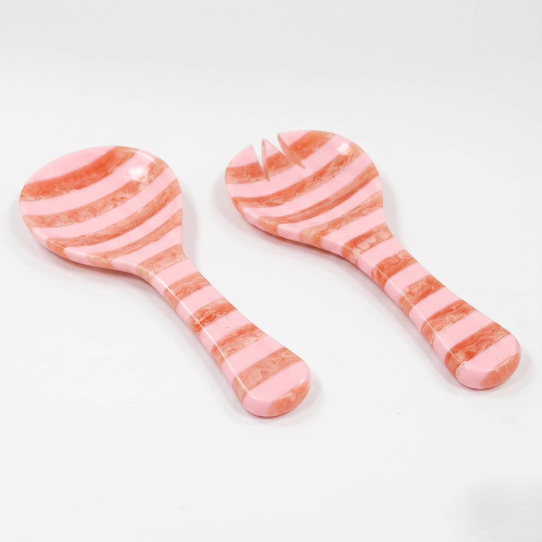 Two pink and peach striped serving utensils, one spoon and one small server with a fork head, on a white background.
