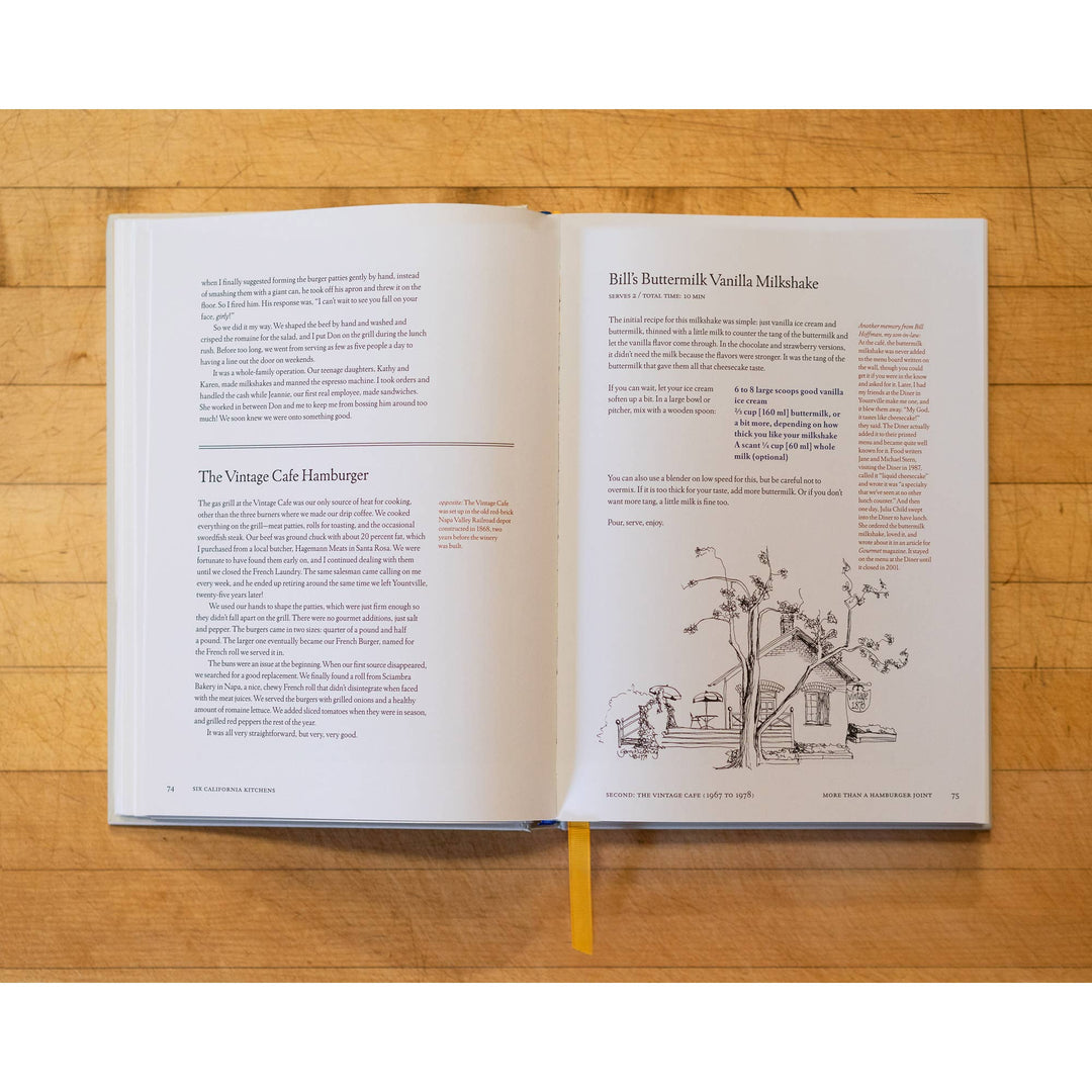 Open book on a wooden surface with text and a small illustration of a house.