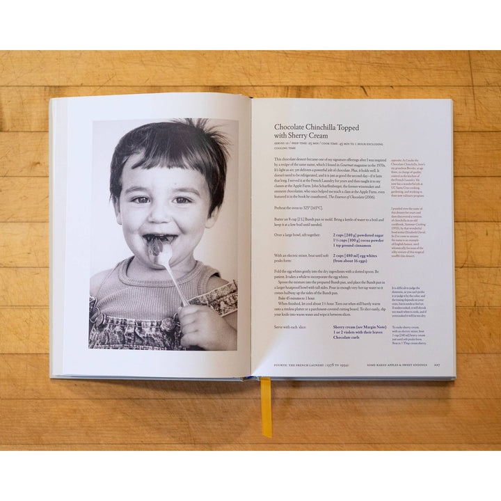 Open book on a wooden surface with a black and white photo of a child and text.