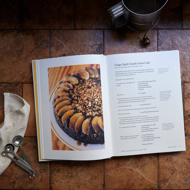 Open cookbook on a wooden table with a cake image and text