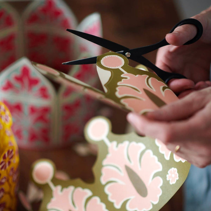 Person cutting out a patterned paper crown with scissors