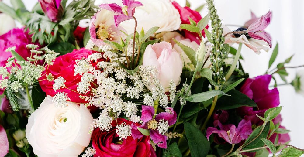 A bouquet of pink white and red valentine flowers designed by charleston street florists including roses ranunculus peonies tulips clematis andd queen annes lace flowers