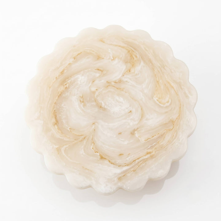 A single scalloped circular product, likely a soap bar or decorative plaque, with a marbled swirl pattern in cream, off-white, and light tan tones, photographed from directly above on a white background.